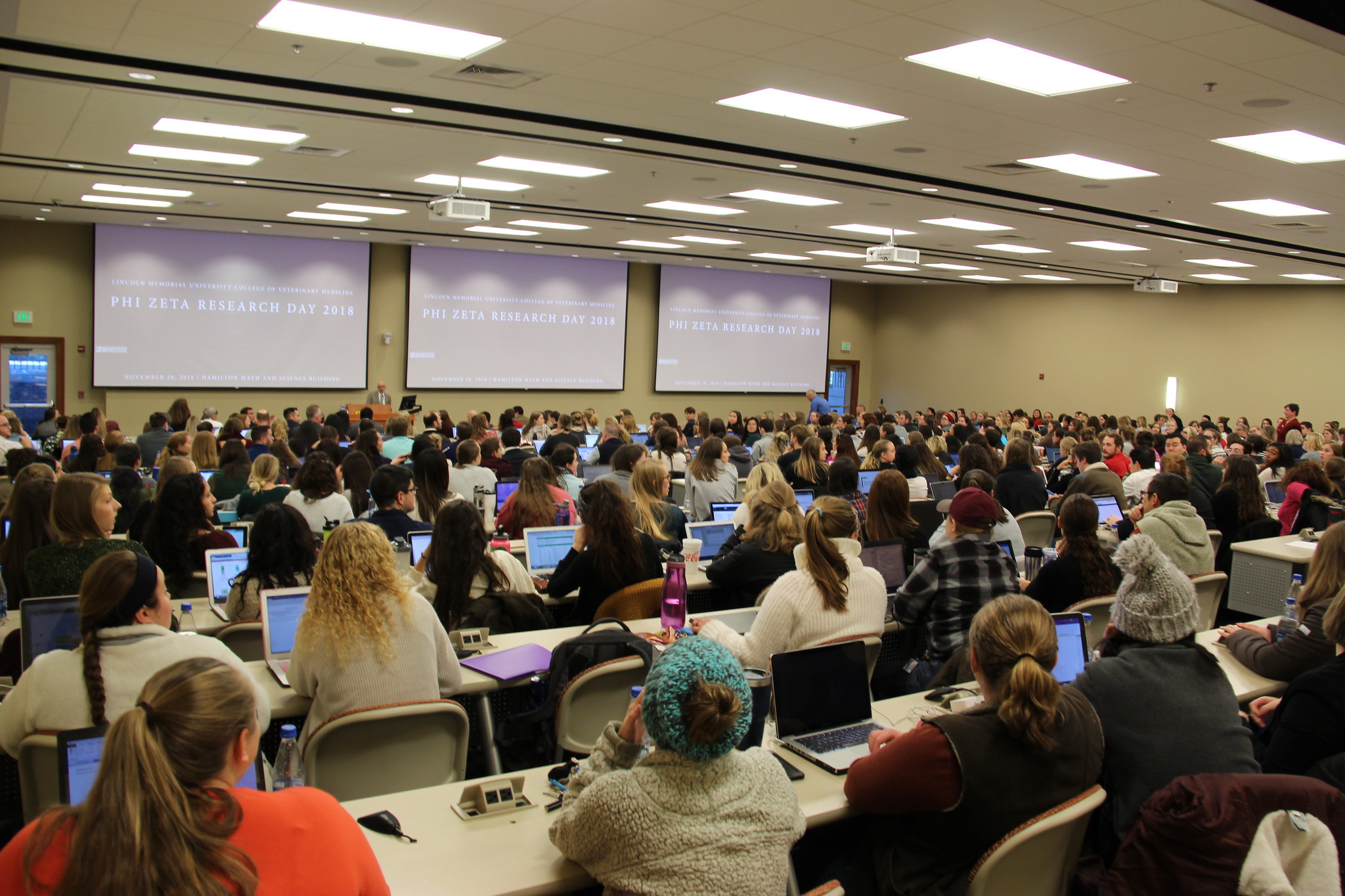 A group of students in a class room looking at a PowerPoint