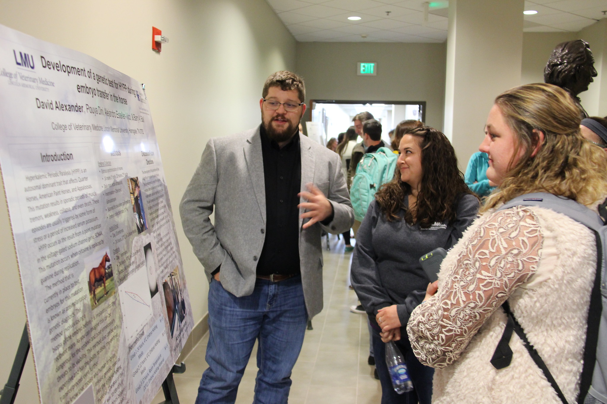 A student explaining his poster presentation to another person