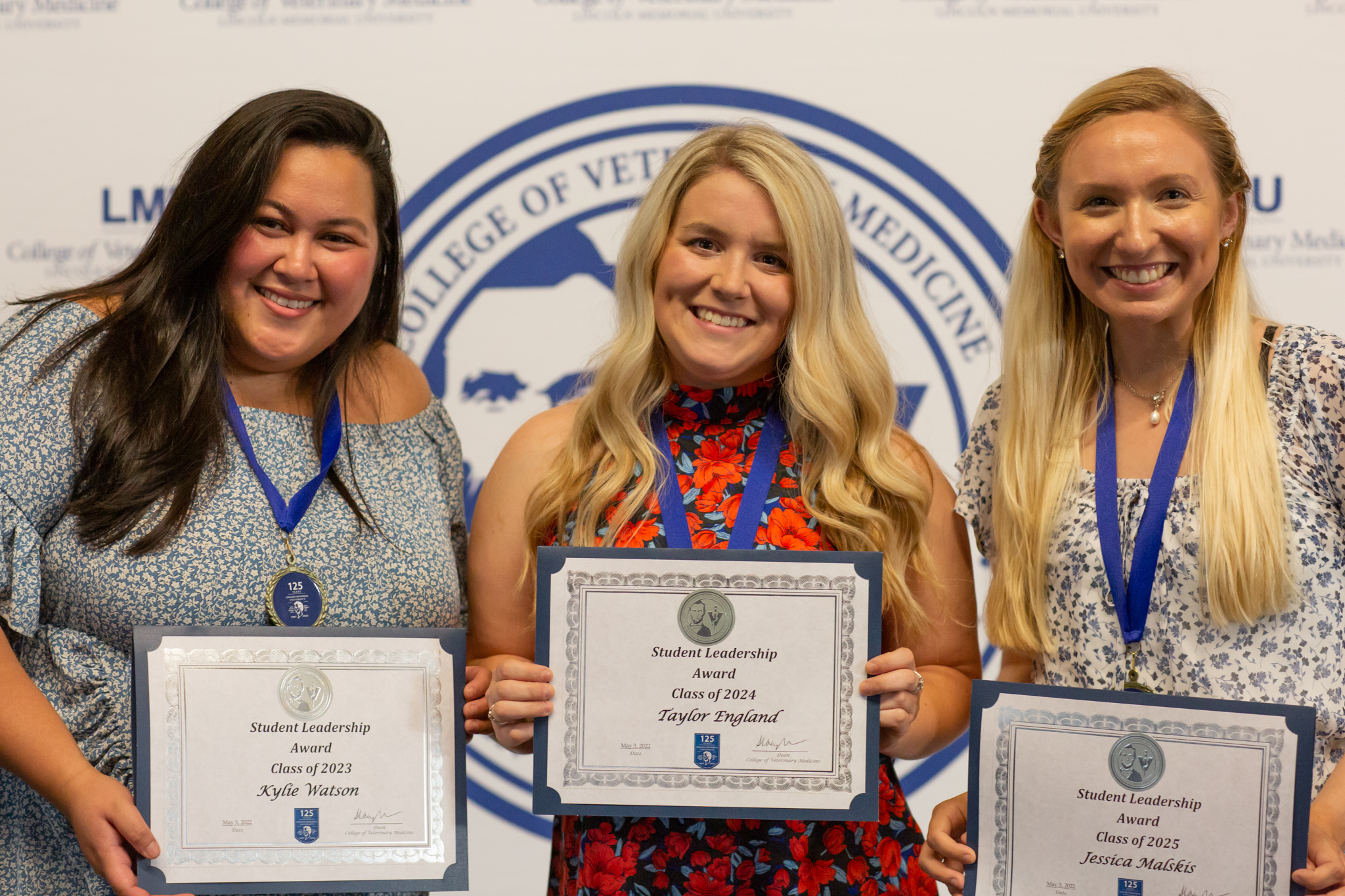 Three women holding up an award and smiling