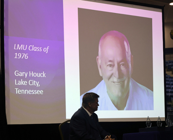 Large projector screen with photo of Gary Houck.