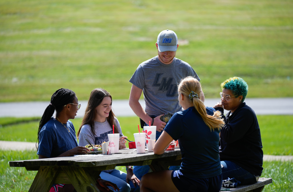 Students eating Chick-fil-A at a picnic table.