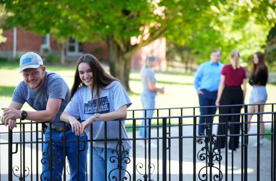 A picture of two students leaning against a rail. 